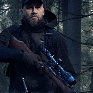 Man holding a bolt-action rifle with a Pulsar Thermion 2 thermal riflescope.